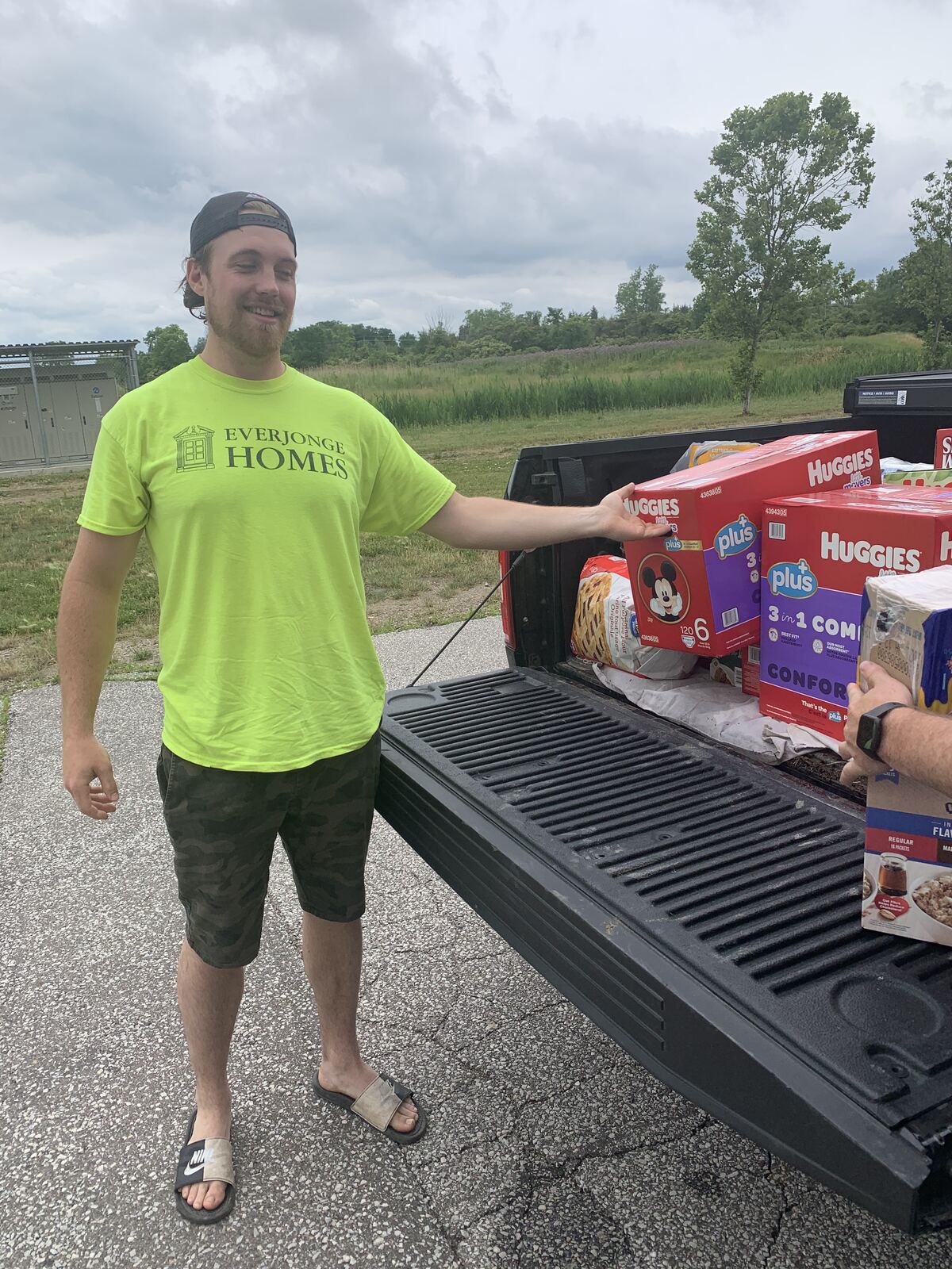 An EverJonge team member beside a truck loaded with donated food and household essentials