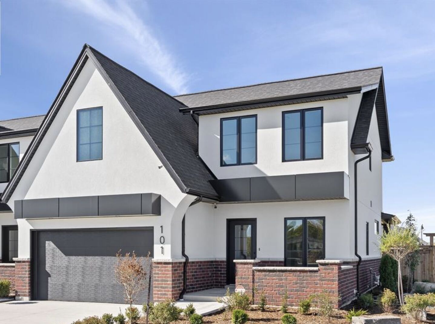 The front elevation of 101 Erie Isle Court — white stucco with a steep dark gable roof, a red brick base and an attached two-car garage