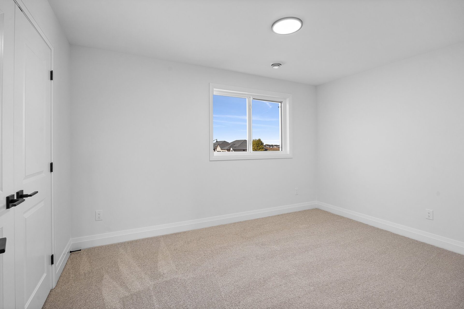 Carpeted secondary bedroom with a window to the rear