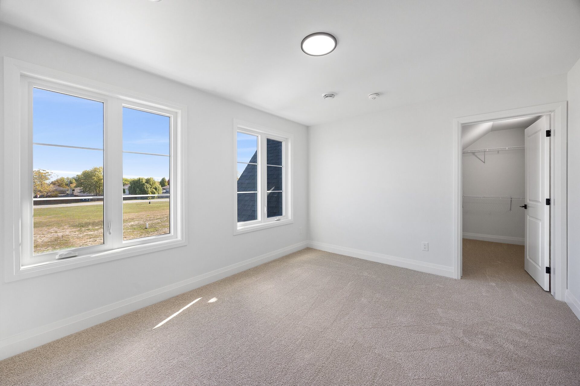 Upper bedroom with windows on two walls and a walk-in closet beyond
