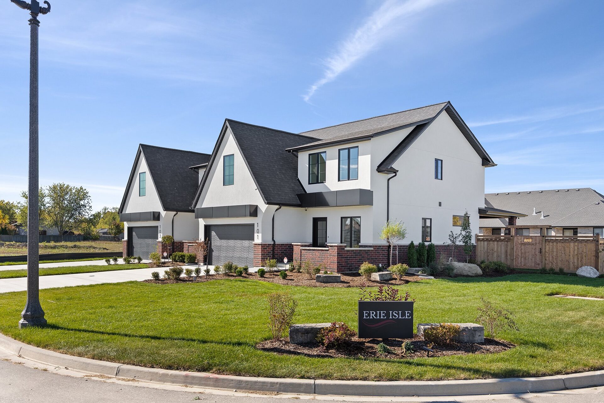 The Erie Isle monument sign on the landscaped lawn at the community entrance, with the semi-detached homes behind