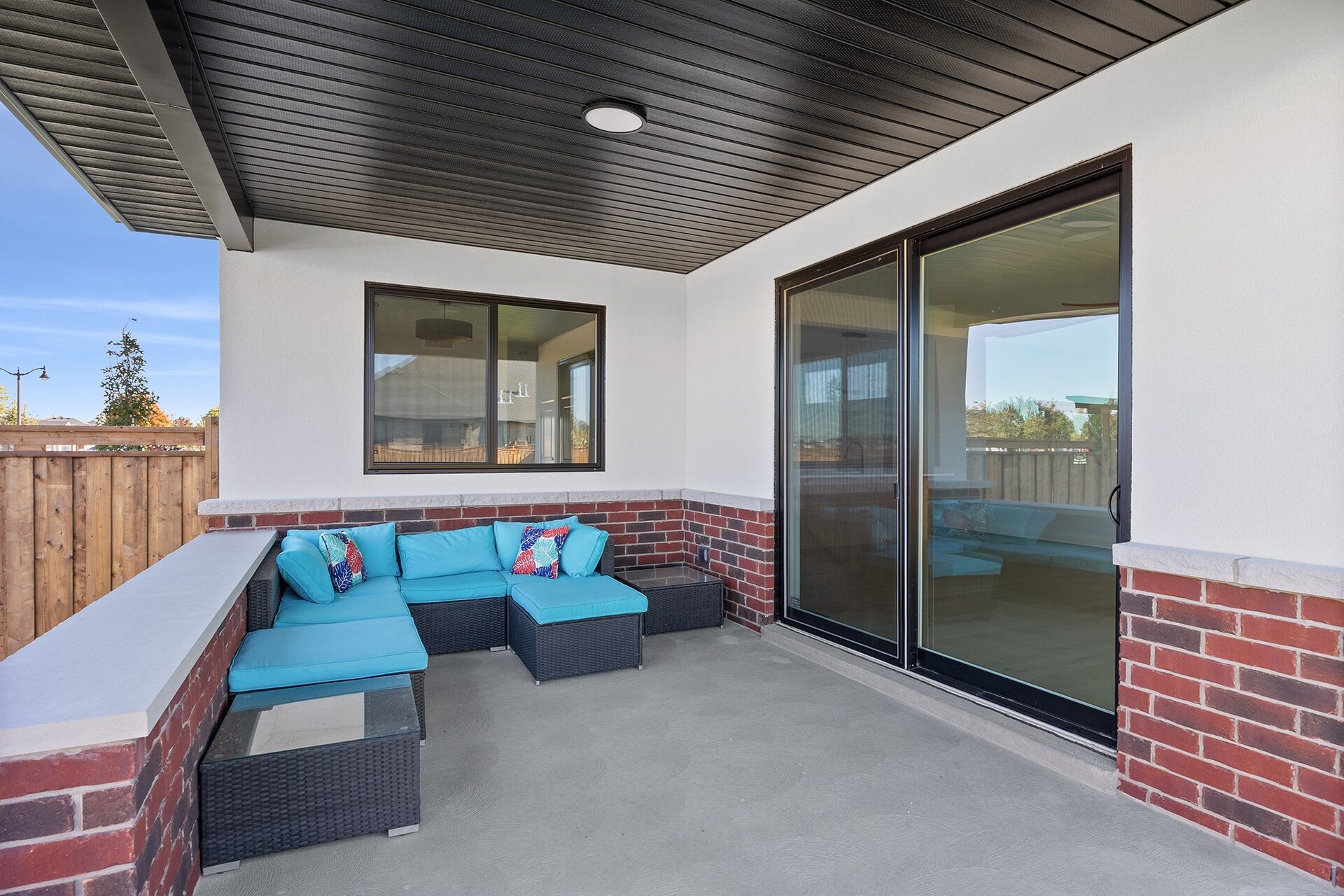 Covered patio with outdoor seating beside the sliding doors to the great room
