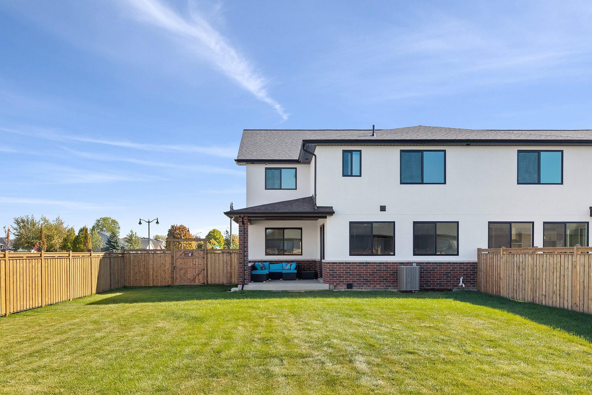 Fenced rear yard with mature lawn and the rear elevation beyond