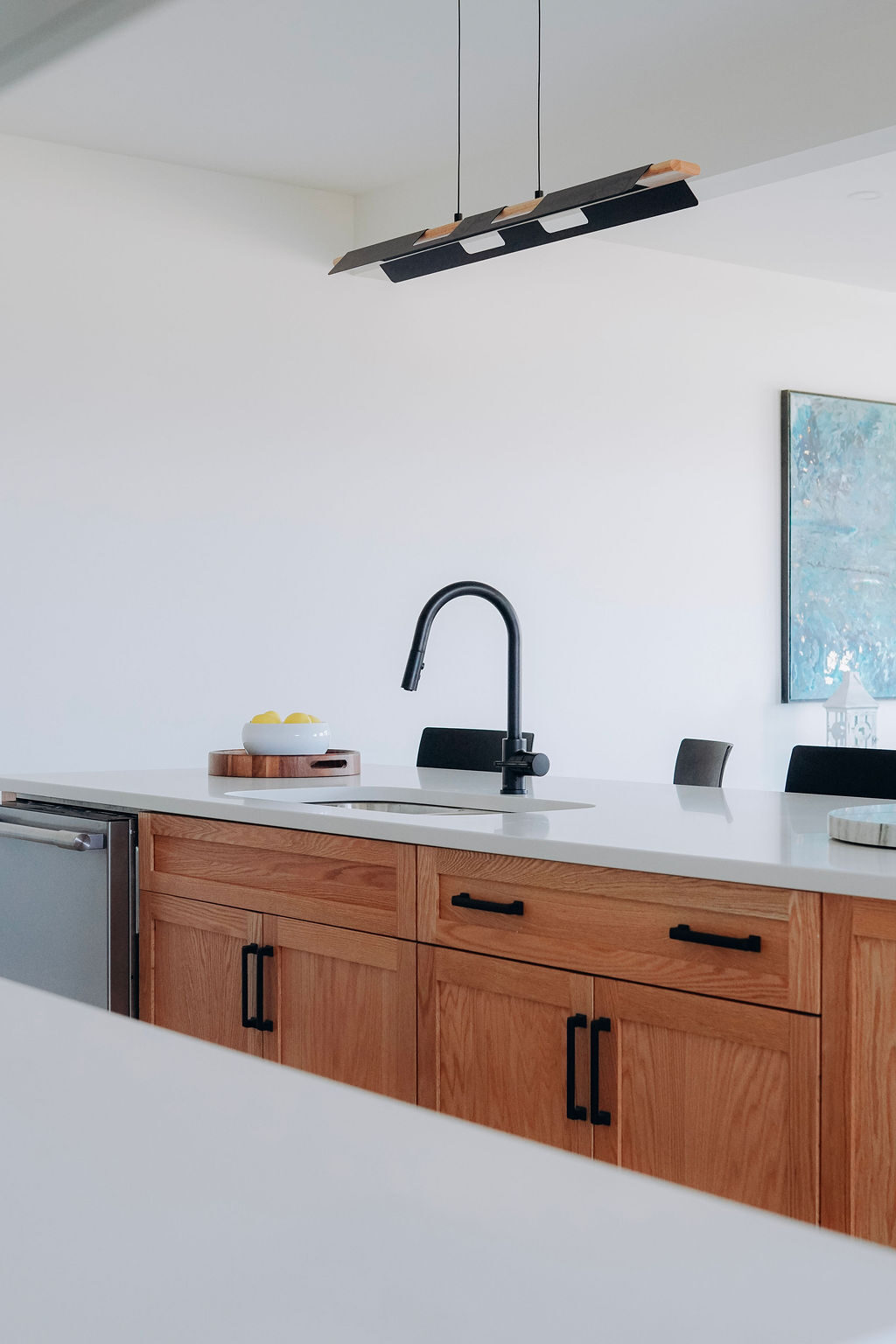 Prep counter in quartz with an undermount sink, black gooseneck faucet and oak cabinetry below