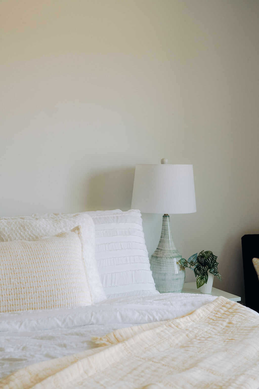 Close view of the layered white bedding and textured pillows against the headboard