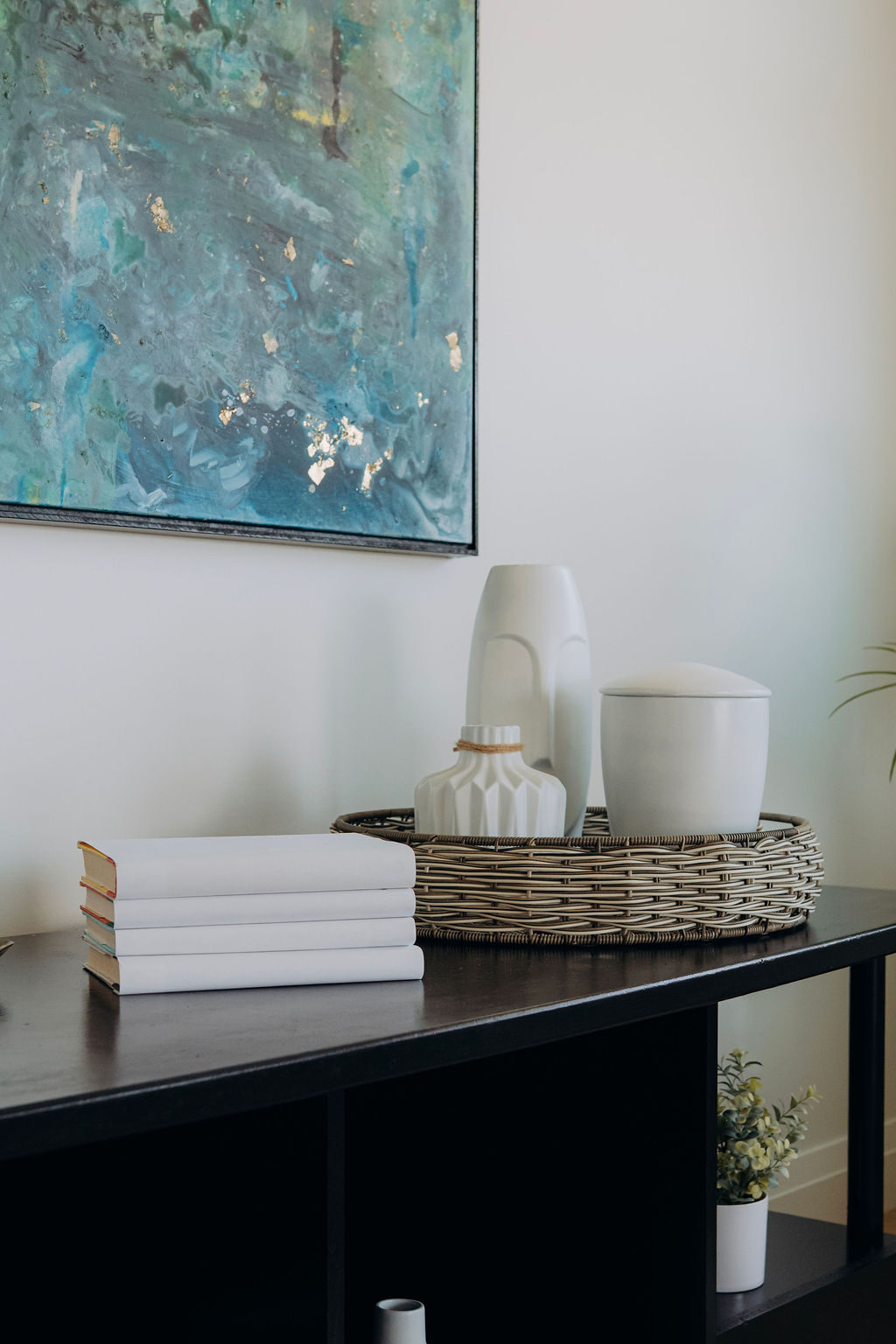Styling detail on the black console, with folded linens in a woven tray and white ceramic vessels