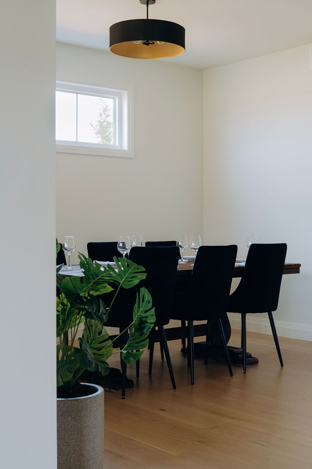 The dining room, with black chairs around a set table beneath a black drum pendant