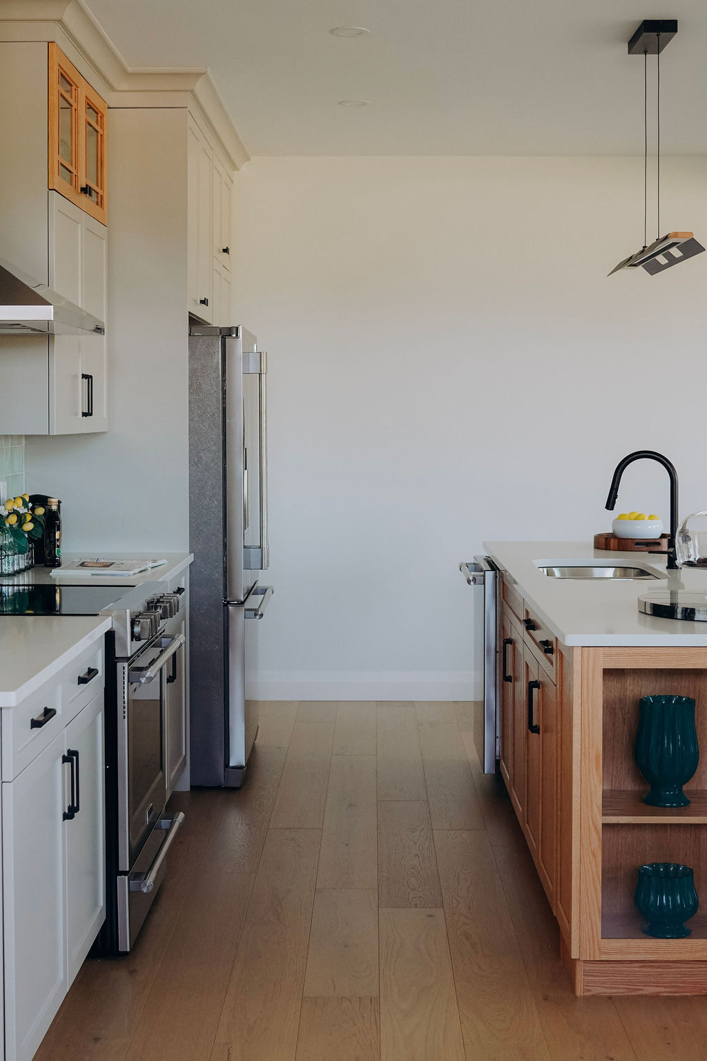 The kitchen run from the great room, with the stainless range and refrigerator and the oak island alongside