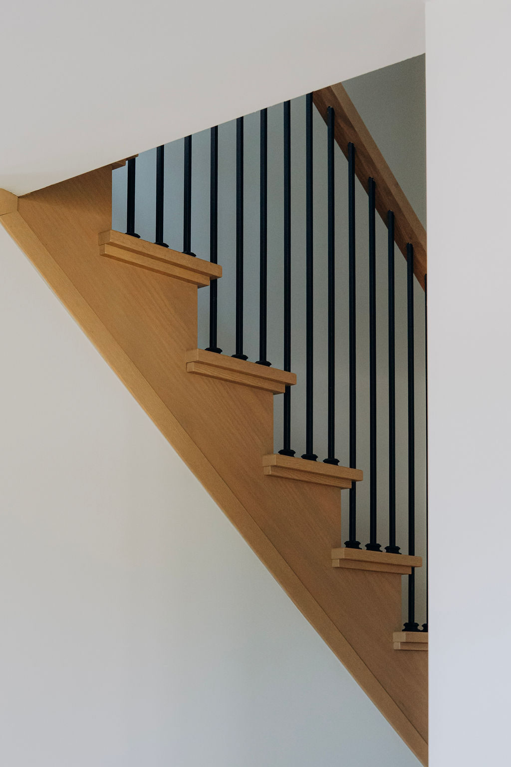 White oak stair treads rising against black metal spindles and an oak stringer